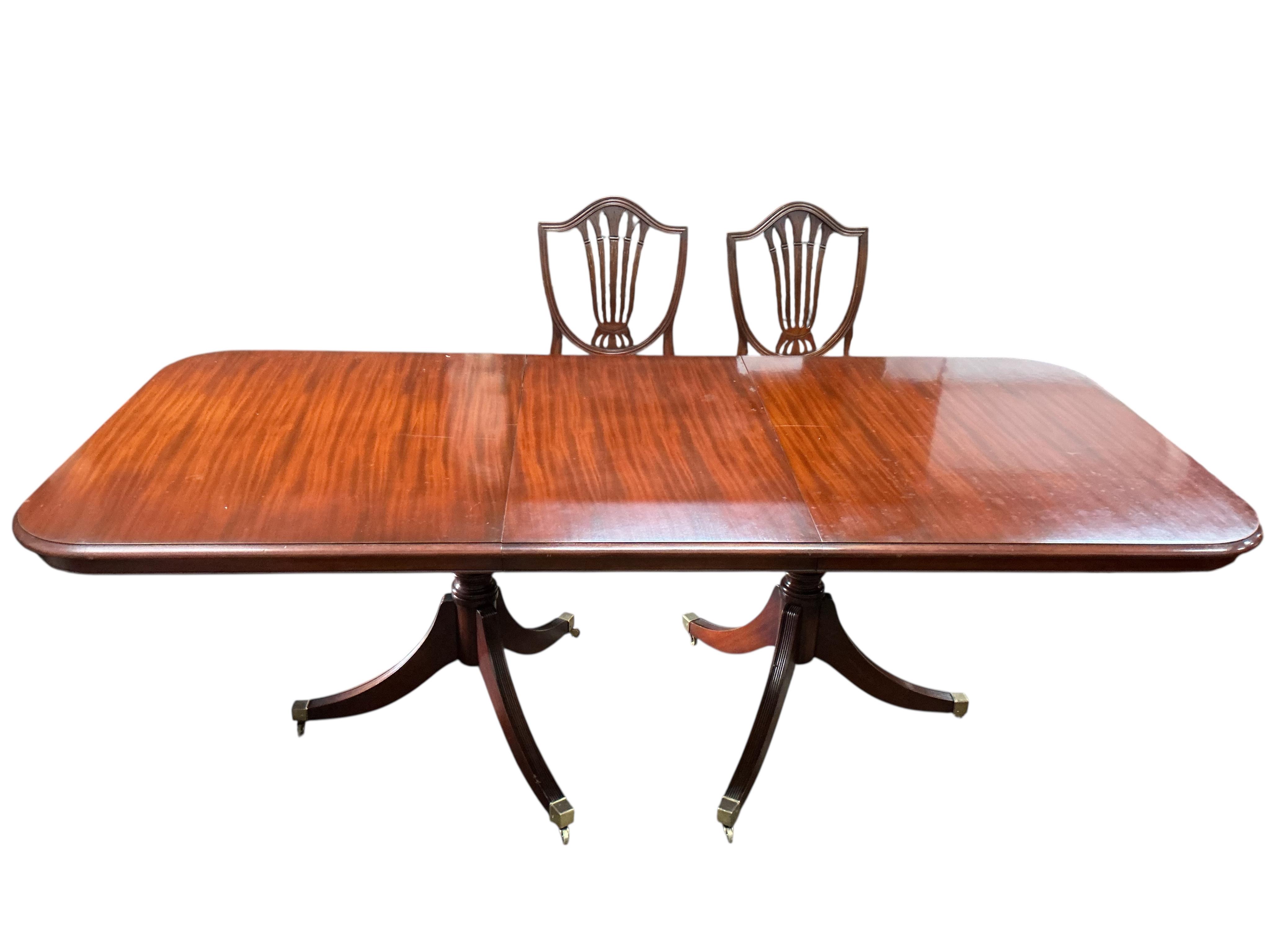 A reproduction mahogany twin pillar extending dining table, 216cm extended, one spare leaf, depth 98cm, height 74cm and eight Hepplewhite style dining chairs, two with arms